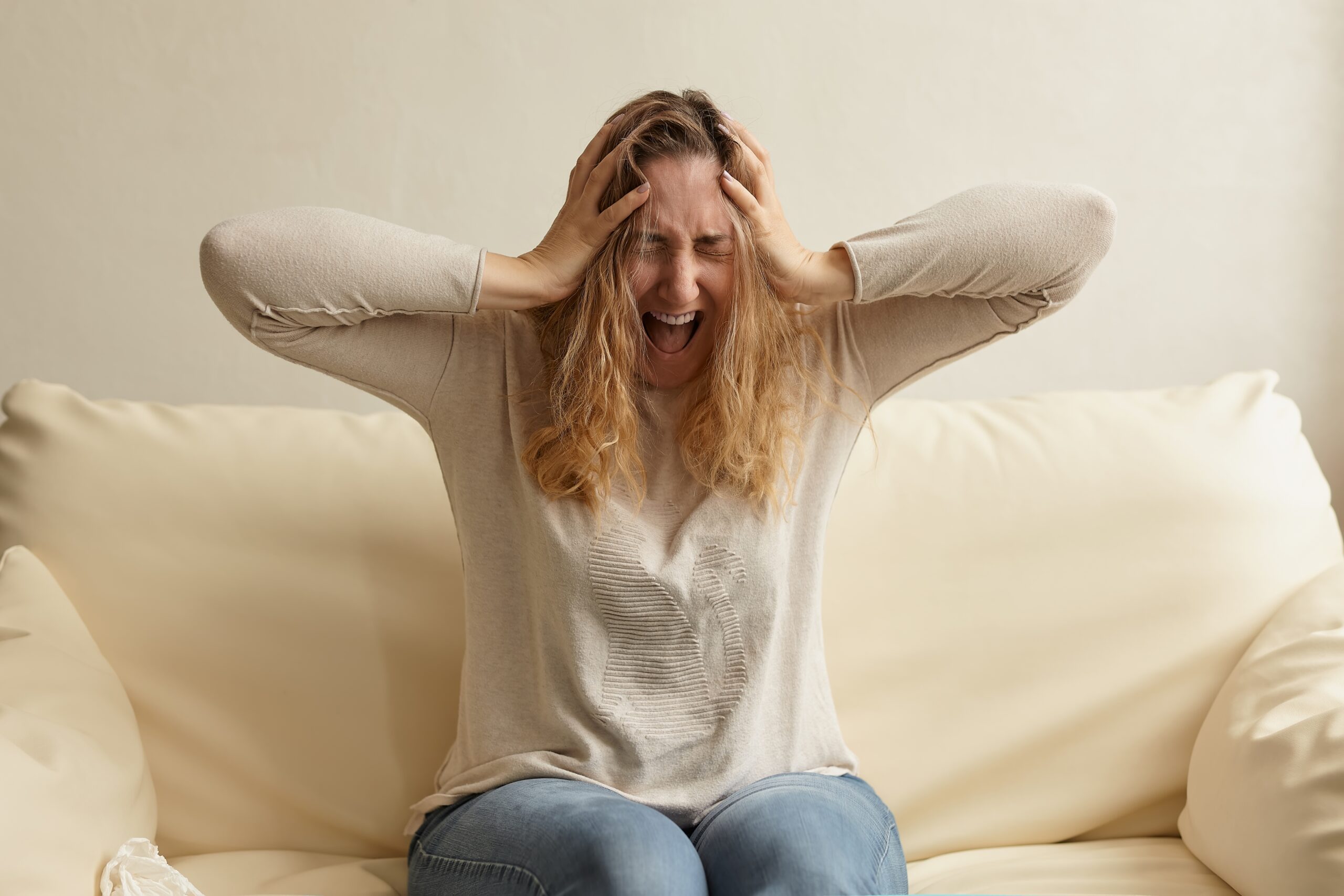 Stressed female worker on sofa covering her eyes